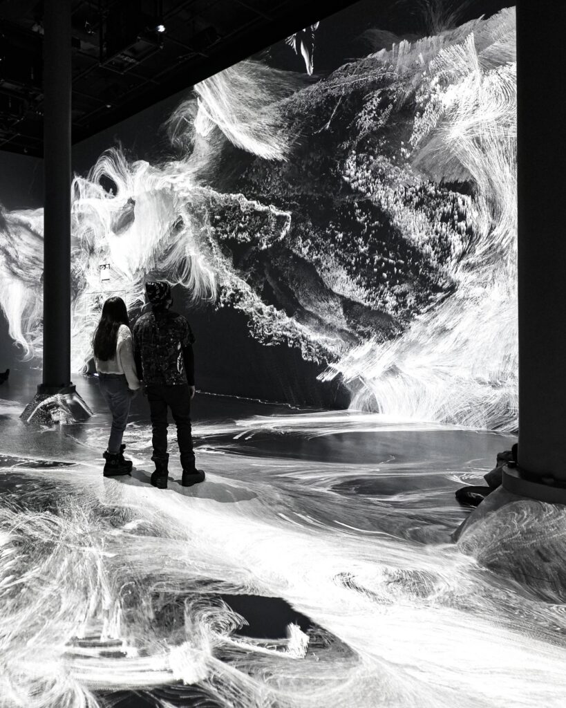 Couple holding hands, looking in awe at immersive art space, black and white high contrast