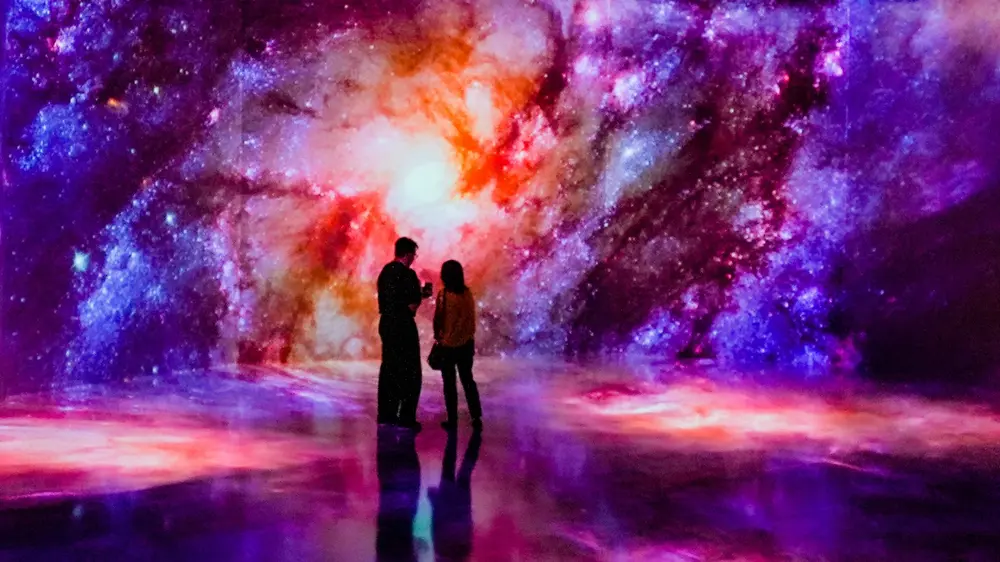 couple looking at each other with immersive galactic background, color spans walls and floor
